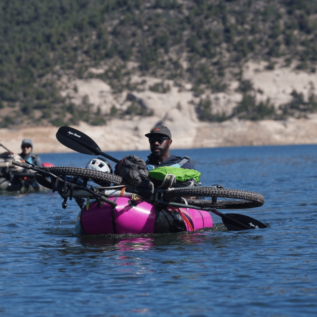 manta ray carbon 2-piece versa-lok kayak paddle being paddled in pick and black packraft with bike on front