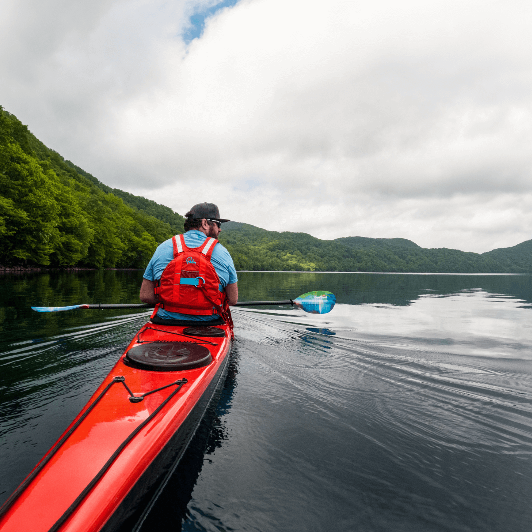 man in red sea kayak paddling with the whiskey fiberglass northern lights paddles#color_northern-lights