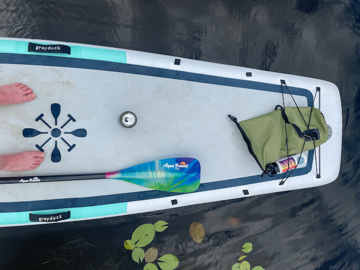 bare feet on SUP board with paddle and dry bag
