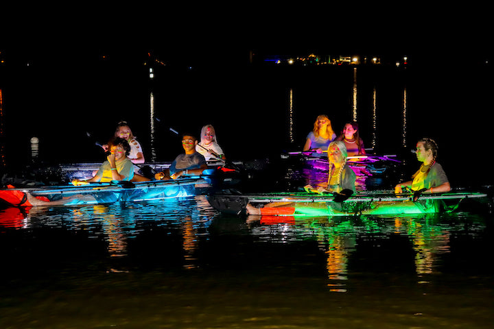 paddlers in glow in the dark kayaks at night