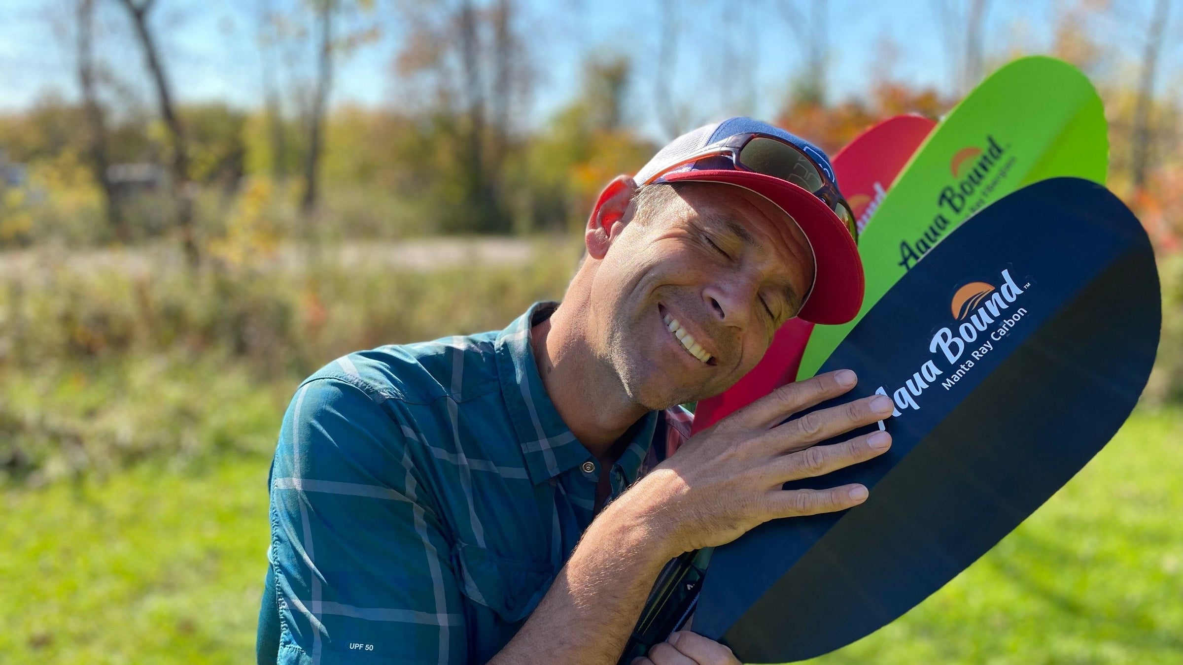 A man lovingly hugging three Ray Series kayak paddles