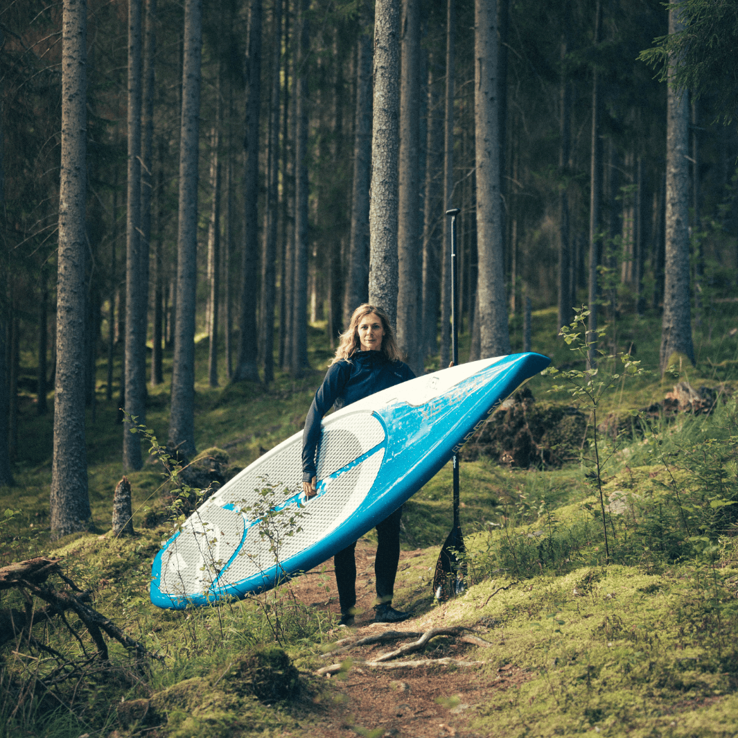 girl standing in woods, hiking with SUP board and challenge 85 2-piece paddle