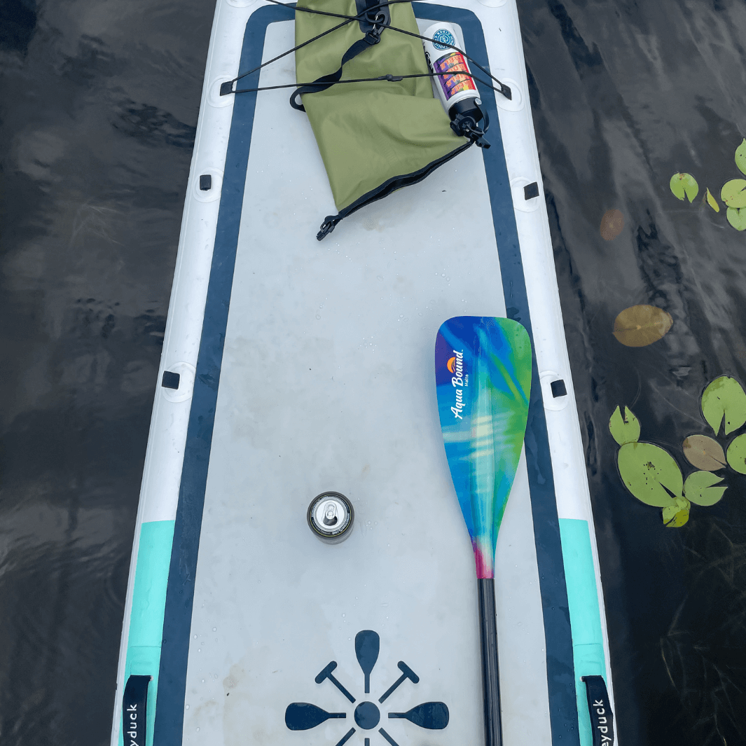 Northern lights pattern SUP paddle laying on Grey Duck SUP board with water lilies#color_northern-lights