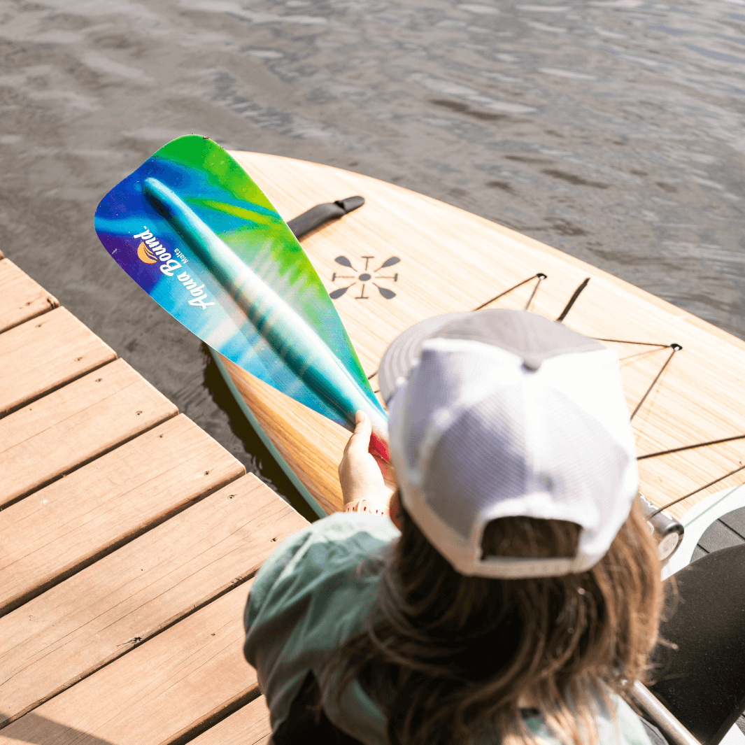 Overhead shot of woman holding northern lights SUP paddle on dock#color_northern-lights