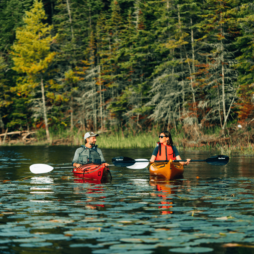 manta ray carbon 2-piece posi-lok kayak paddle being paddled by woman in kayak next to man in kayak paddling with the manta ray hybrid white