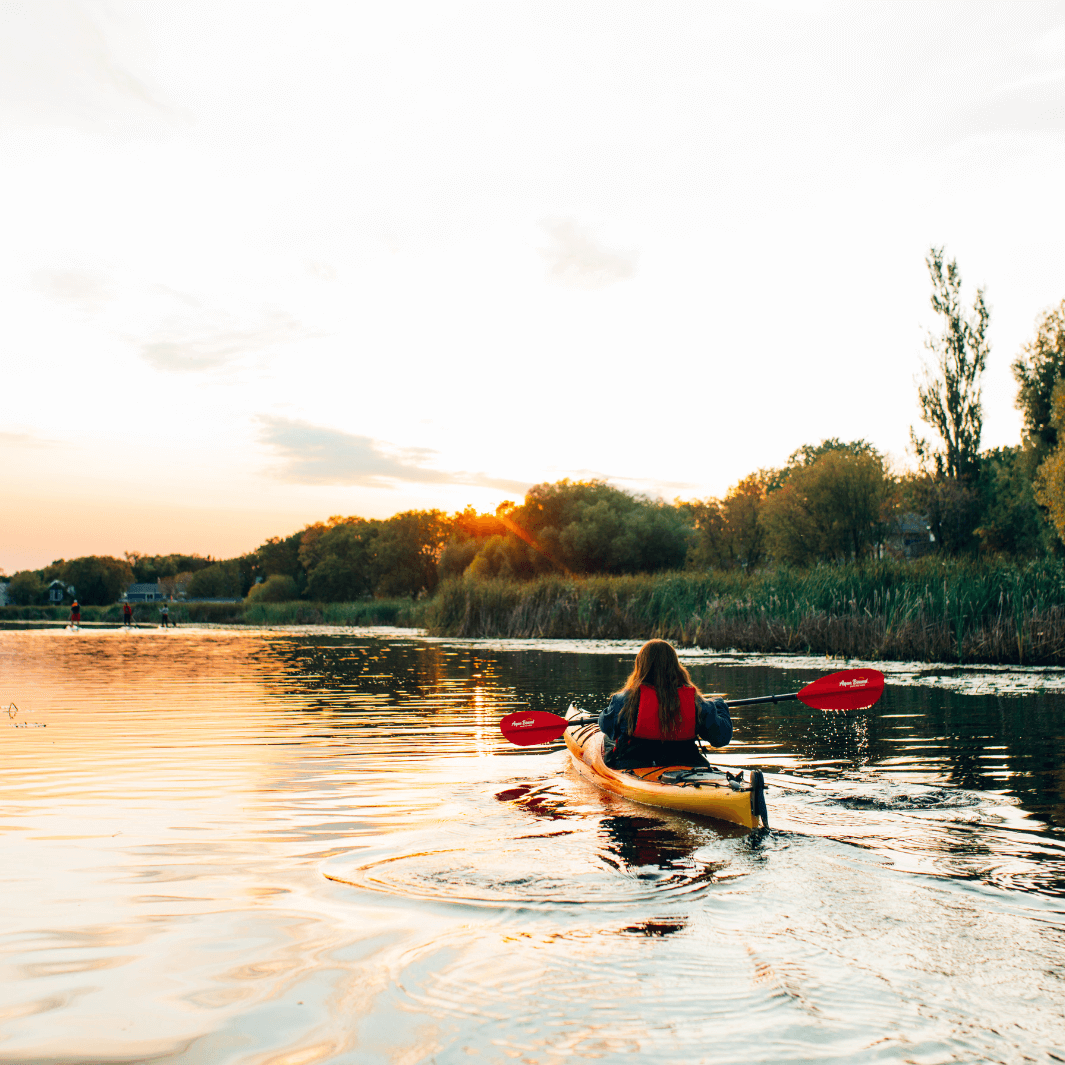 manta ray hybrid 2-piece versa-lok sunset red being paddled by a female in yellow kayak during evening time with sun setting#color_sunset-red