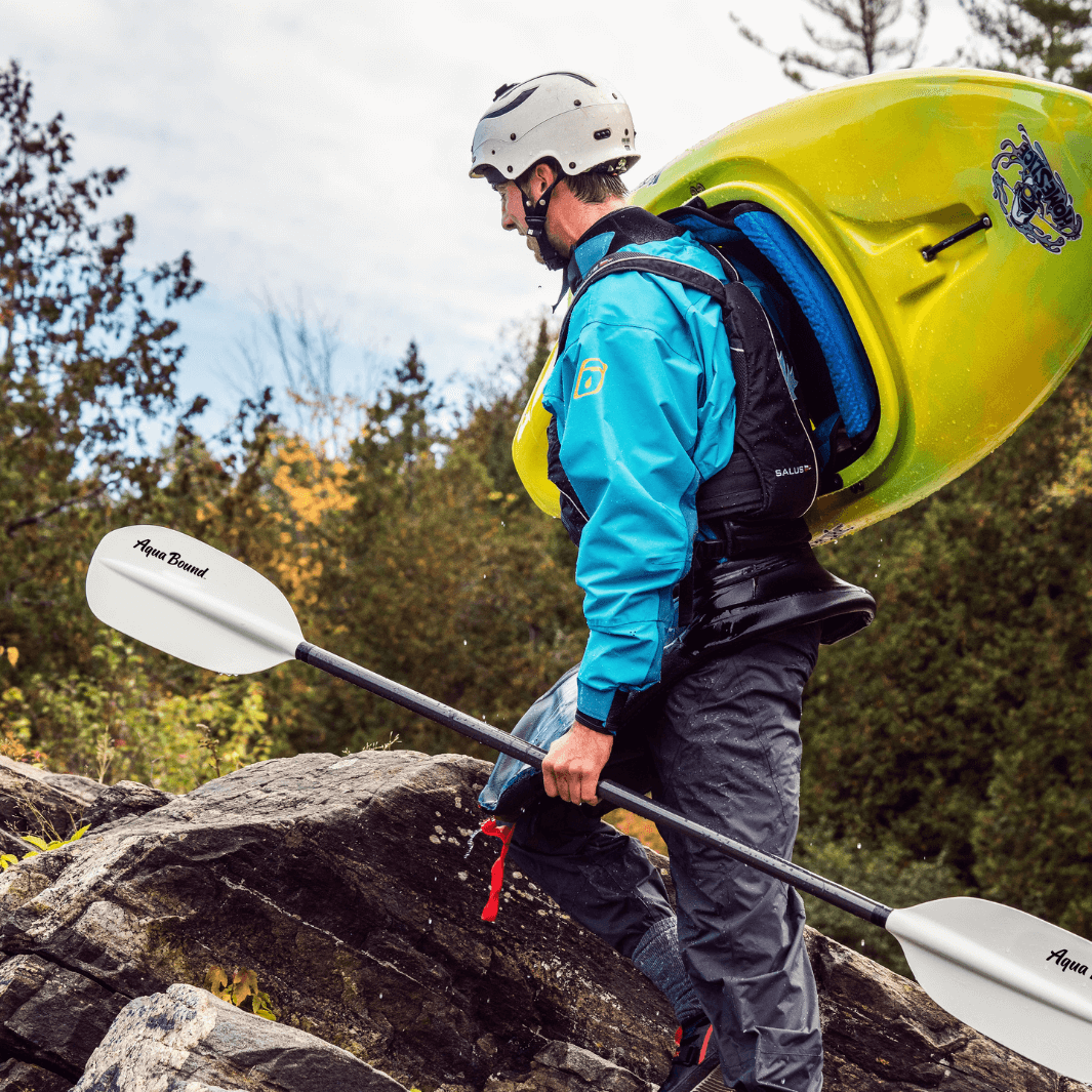 whitewater kayaker brings kayak and shred hybrid paddle up rocks