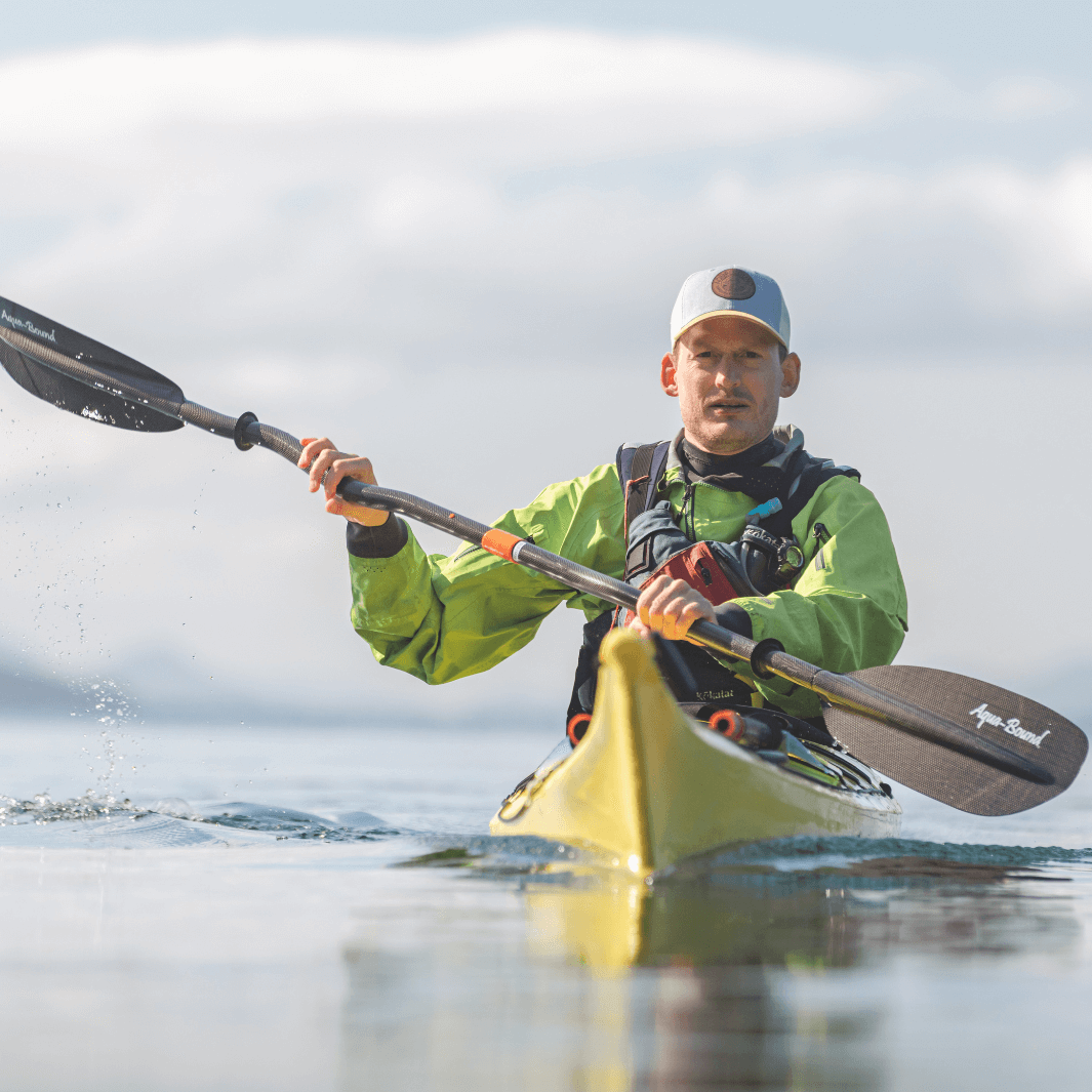 male sea kayaker paddling towards camera with tango carbon bent shaft kayak paddle