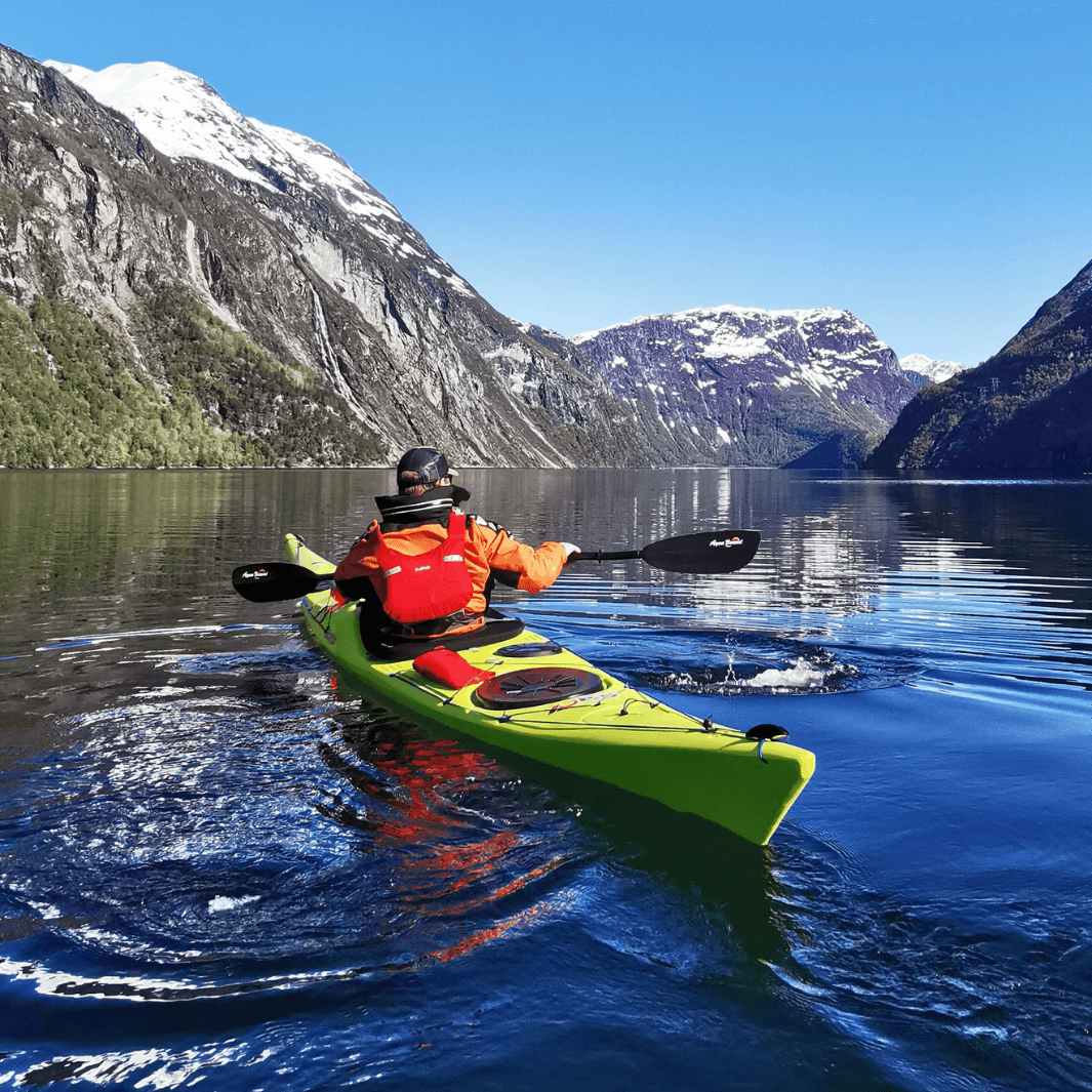 male sea kayaker paddling with tango carbon bent shaft with snow capped mountains in background