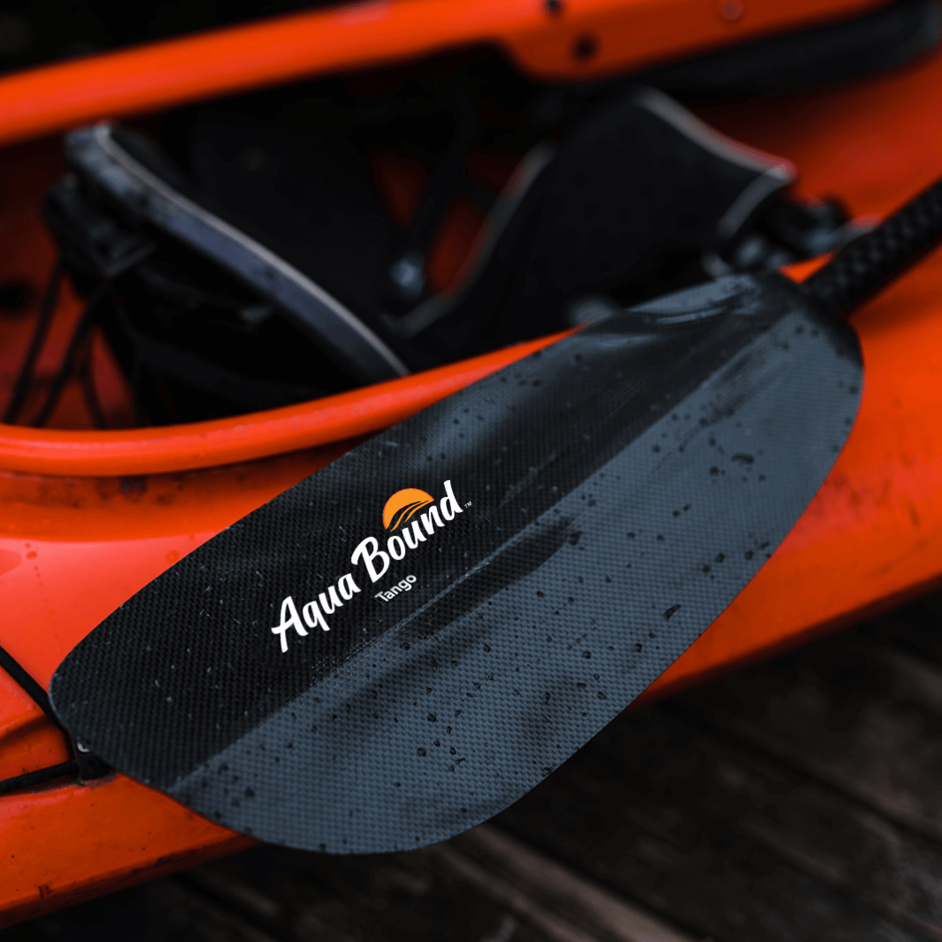 tango carbon 2-piece posi-lok kayak paddle close up laying on red/orange kayak on dock