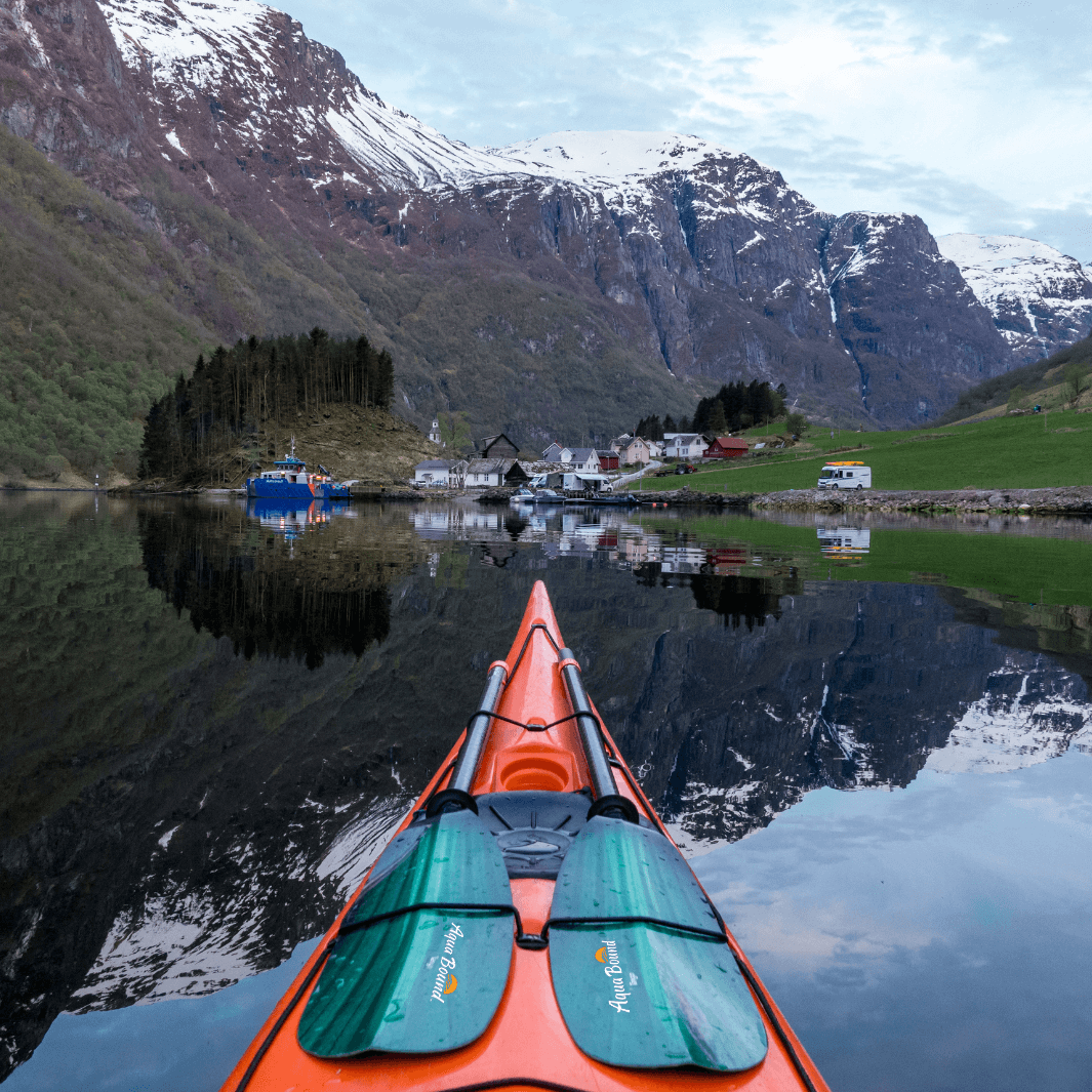 tango fiberglass 2-piece posi-lok kayak paddle green tide in bungies of orange sea kayak mirror reflected mountain range in water in Fjords of Norway#color_green-tide