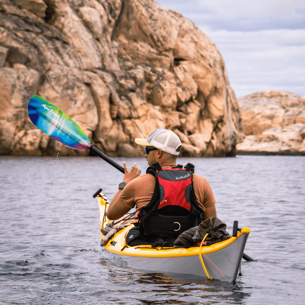 tango fiberglass 2-piece posi-lok kayak paddle northern lights being paddled away from camer man in yellow kayak cliff formations in background#color_northern-lights